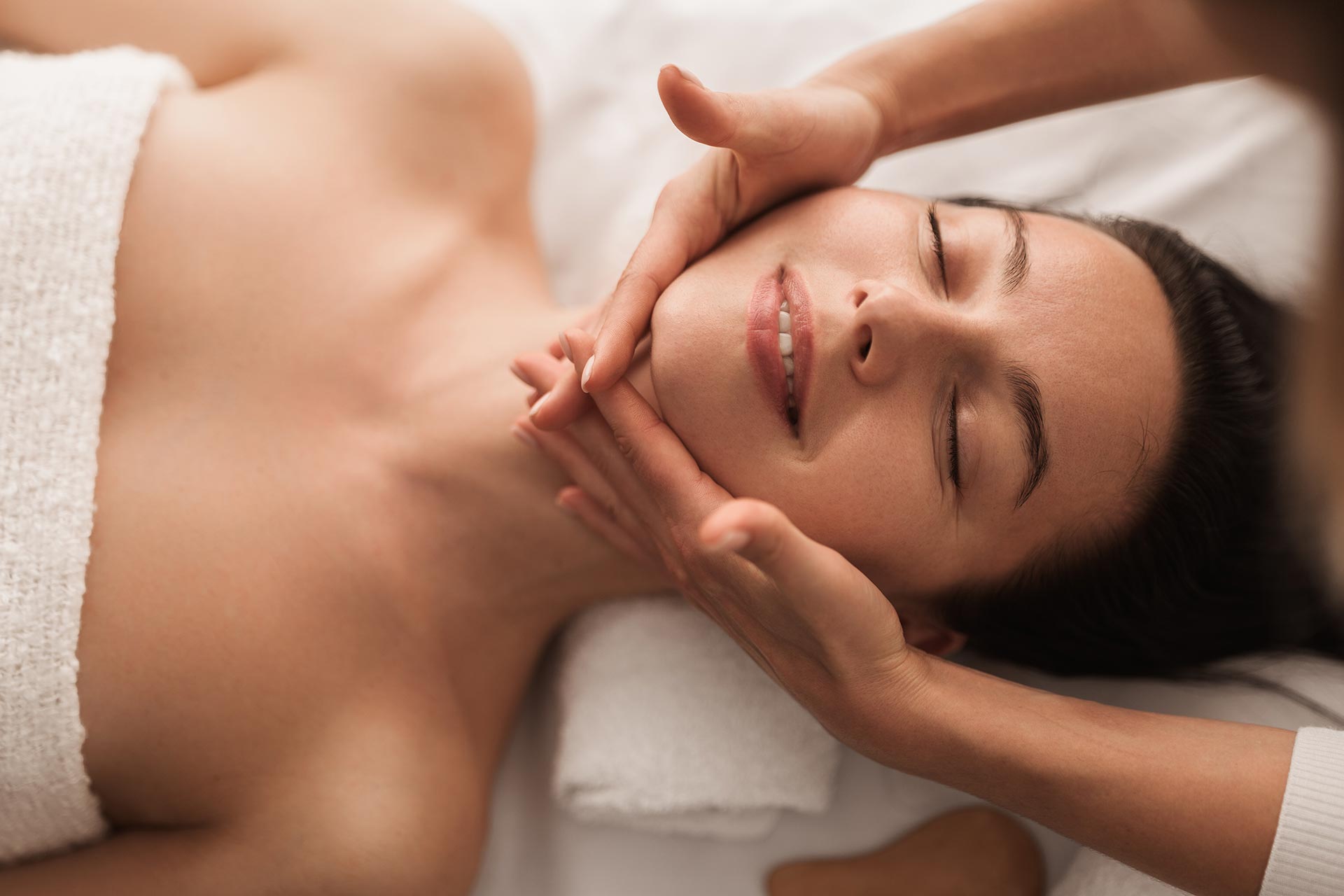 Relaxation body massage being enjoyed by a young beautiful brunette-haired woman.